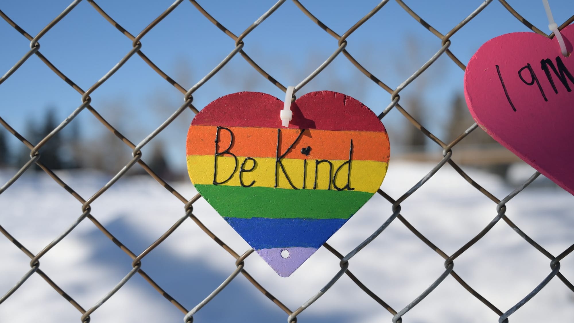 Note saying Be Kind attached to a chain-link fence