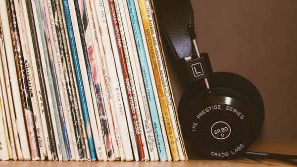 Set of headphones leaning against a stack of vinyl records