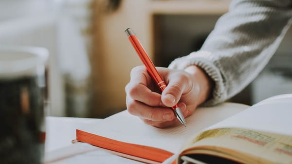 Person using a ballpoint pen to write in a notebook